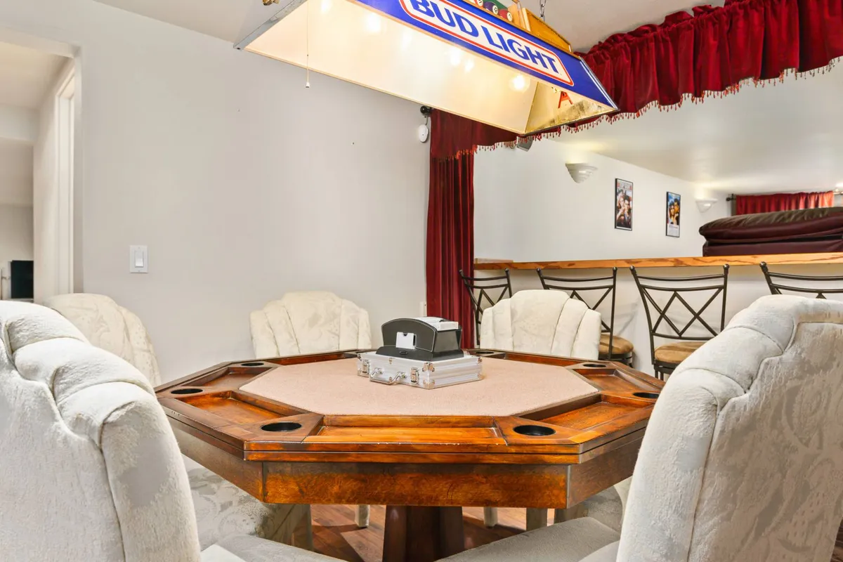 A stylish interior view focused on an octagonal poker table, surrounded by plush seating and illuminated by a Bud Light light fixture, creating an inviting space for lively card games and social gatherings.