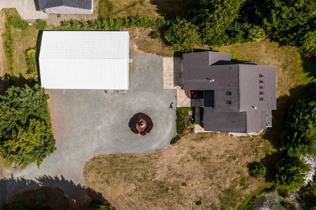 The main house and an outbuilding are set around a central circular garden feature. The lush landscaping and open outdoor spaces evoke opportunities for gardening, family gatherings, or peaceful moments between excursions to local destinations.