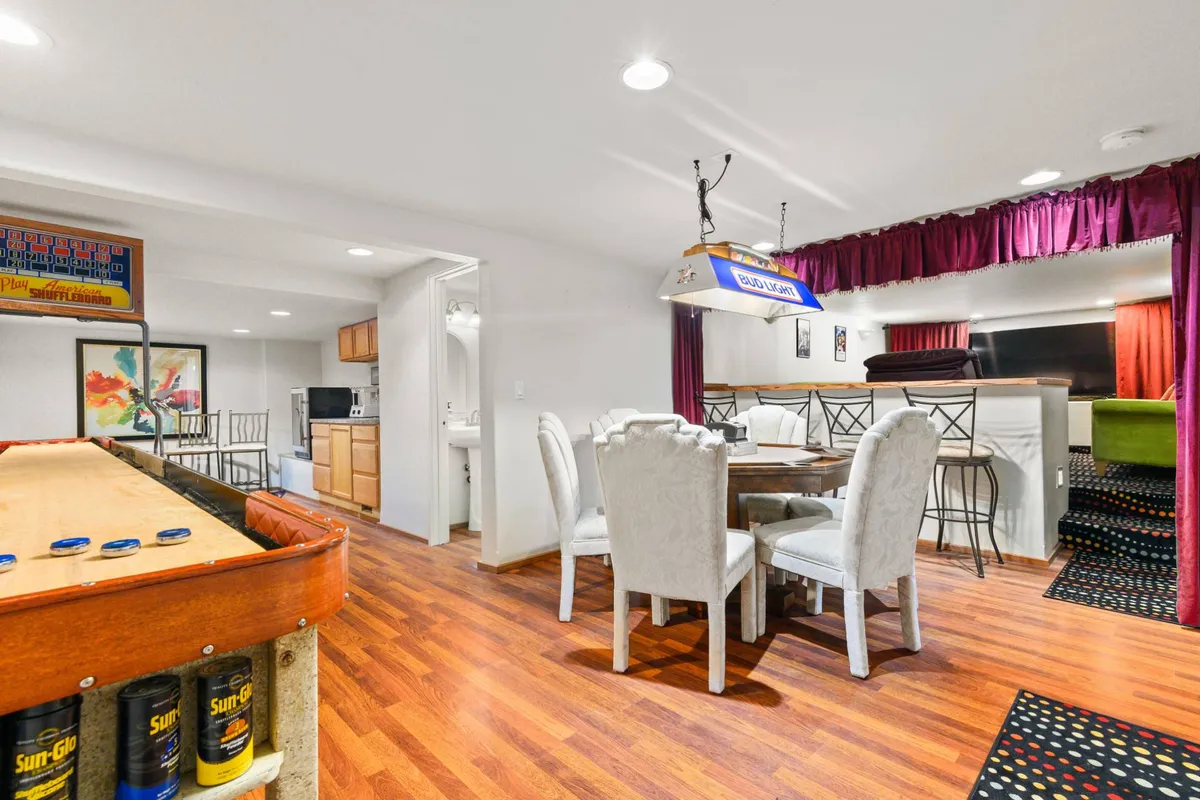 A lively interior scene with a dining table, bar area, vibrant pool table, and colorful drapes. The room radiates energy, emphasizing social gatherings and friendly game nights, perfectly evoking the fun, competitive spirit highlighted in the section.