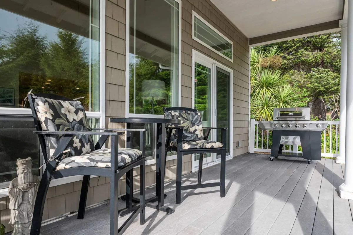 A well-appointed outdoor seating area framed by lush greenery, featuring a BBQ grill and ample space for relaxation or entertaining guests. The inviting setup suggests the ease of hosting festive gatherings or simply unwinding in a tranquil environment.
